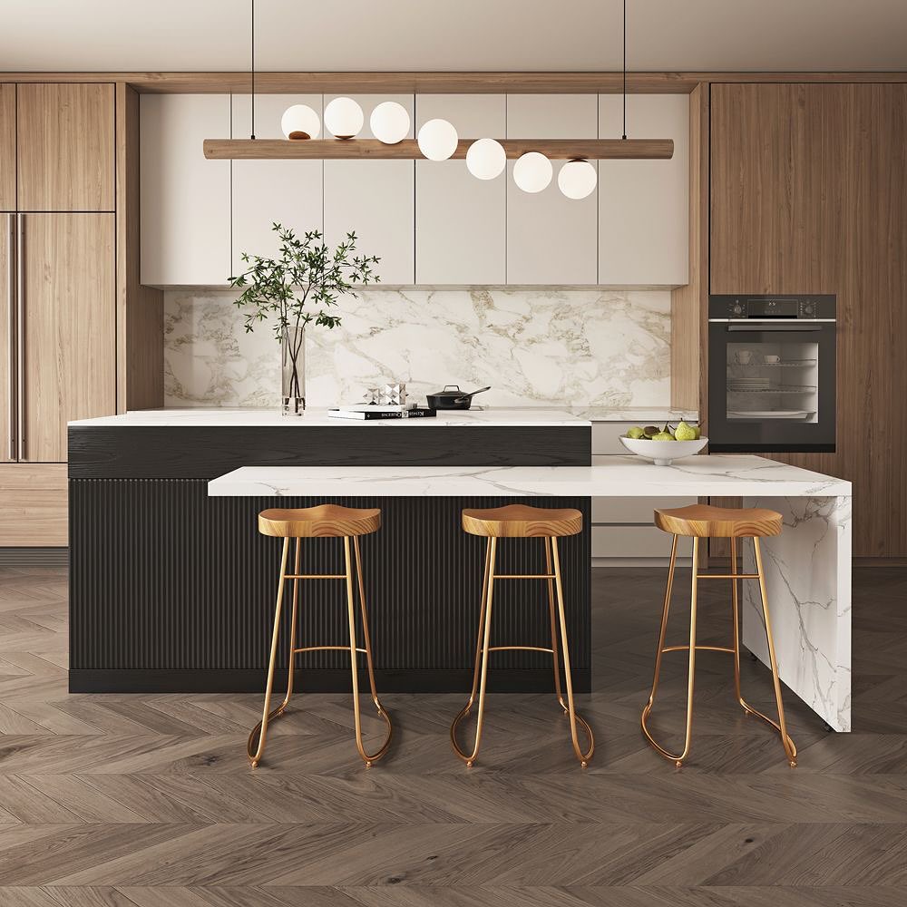 Long black fluted island paired with a white marble waterfall counter extension, three gold-legged bar stools with wood seats, and a row of globe pendants above