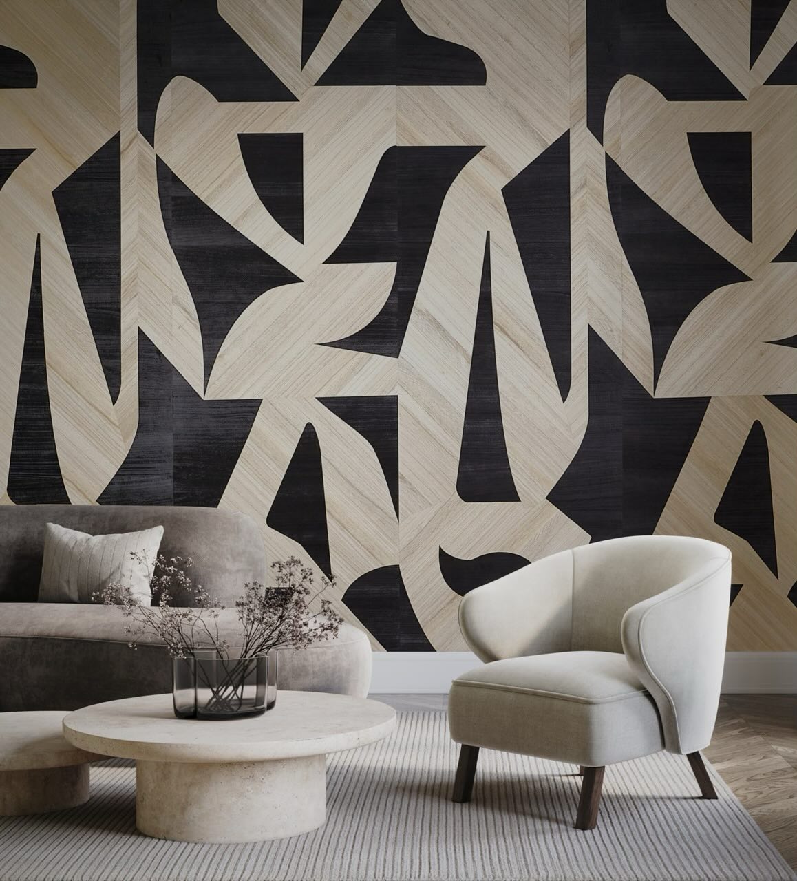 Bold black and light wood veneer geometric cut-out shapes on a feature wall behind a gray curved sofa and cream accent chair, with a round travertine coffee table holding a glass vase of dried branches
