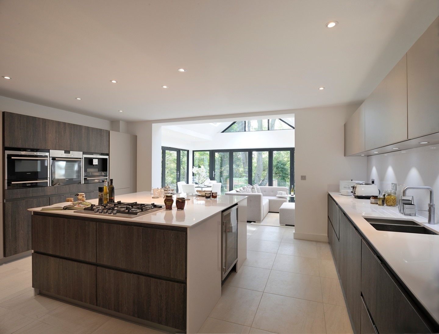 Dark charcoal island with brushed stone countertop paired with light wood perimeter cabinets, floating shelves, and sputnik pendant lights Caption: Charcoal Island Paired With Light Wood