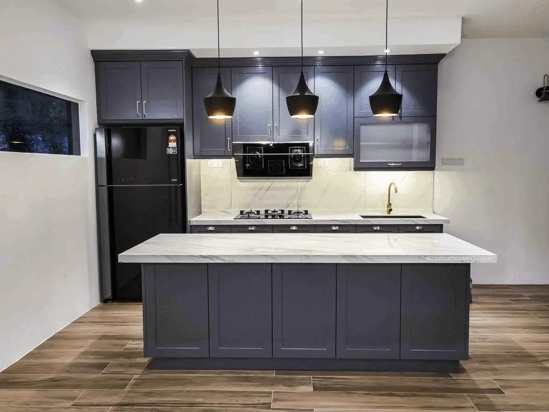 harcoal grey shaker kitchen with large marble top island, three black cone pendants, gold tap, white marble backsplash, black fridge, built-in oven, and wood-look tile flooring