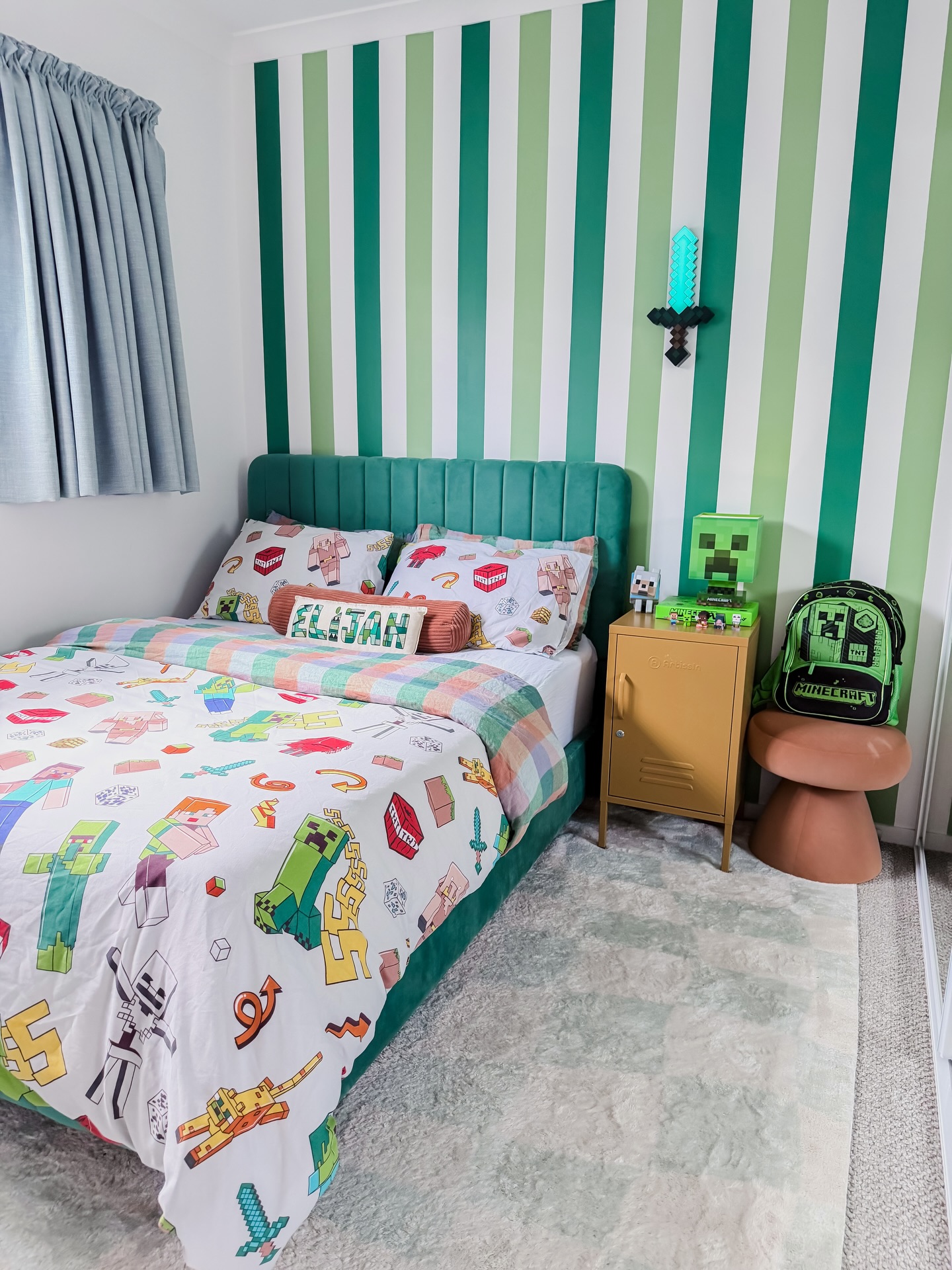 t: Minecraft kids bedroom with green and white vertical striped accent wall teal velvet channel tufted headboard mustard yellow nightstand and Creeper backpack